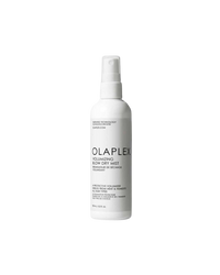 A white spray bottle labeled Olaplex Volumising Blow Dry Mist, with product information and branding visible.
