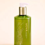 Green bottle with gold cap labeled 'VOYA' on a beige background