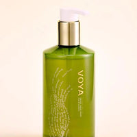 Green bottle with gold cap labeled 'VOYA' on a beige background