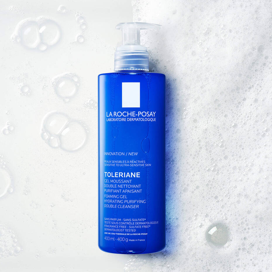 La Roche-Posay Toleriane cleanser bottle on a textured white background with bubbles.