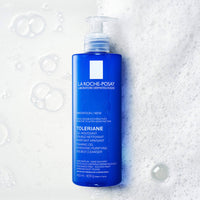 La Roche-Posay Toleriane cleanser bottle on a textured white background with bubbles.