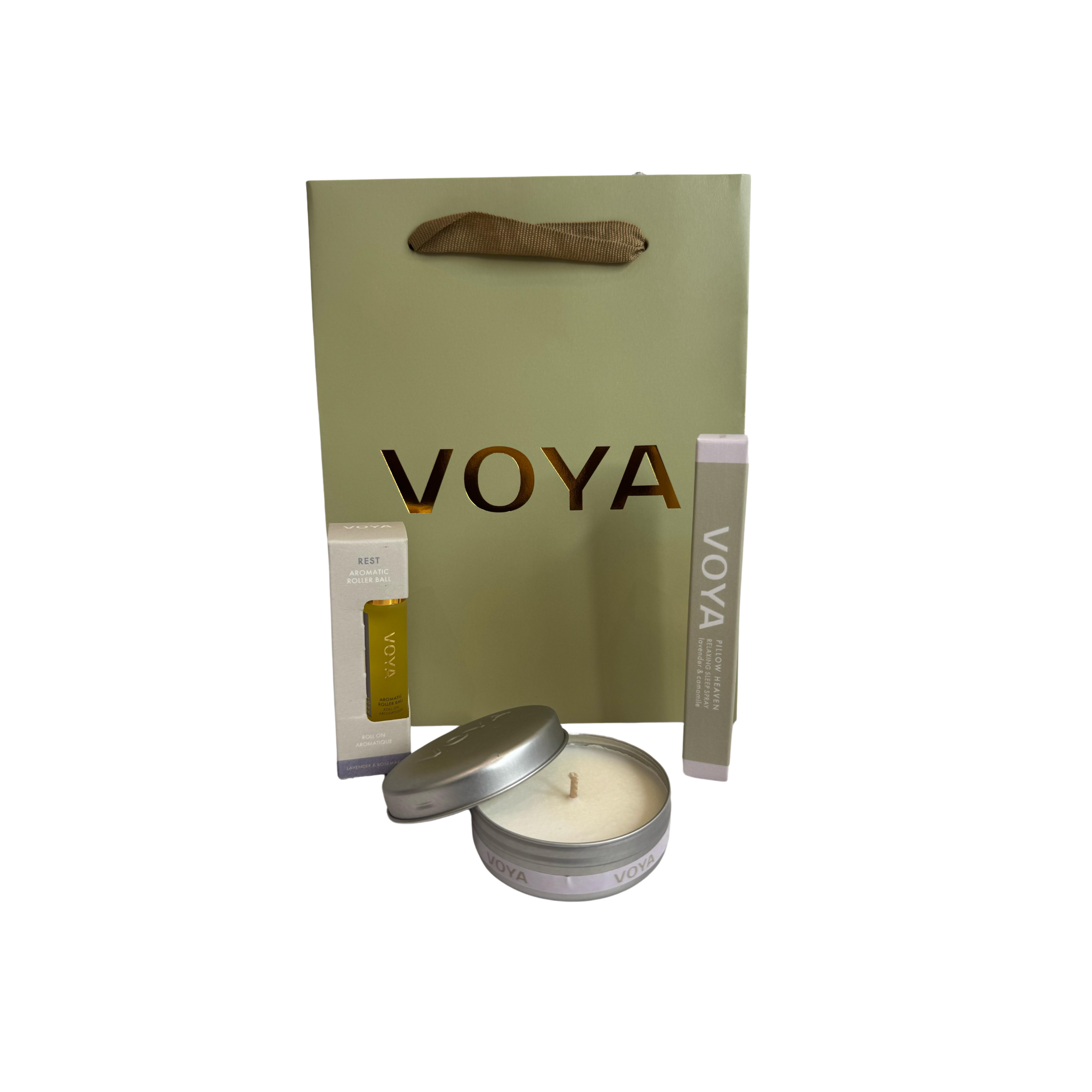 A gift set from Voya, including a relaxing sleep spray, a mini scented candle, and an aromatic roller ball, all displayed in front of a Voya branded paper bag.