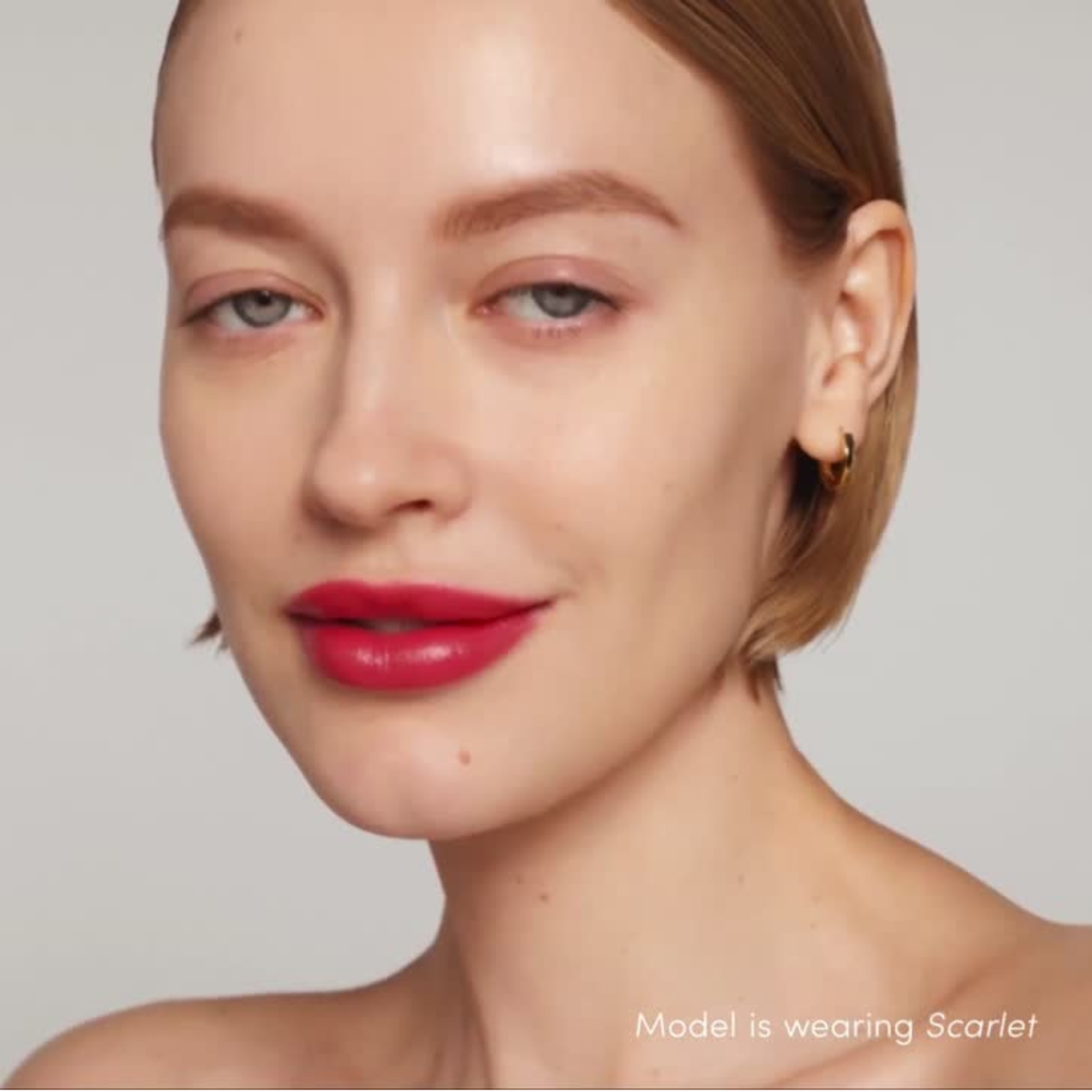 Close-up of a model wearing Jane Iredale Colorluxe lipstick in 'scarlet' with a neutral background