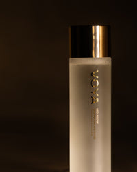 Skincare bottle with gold cap on a dark background