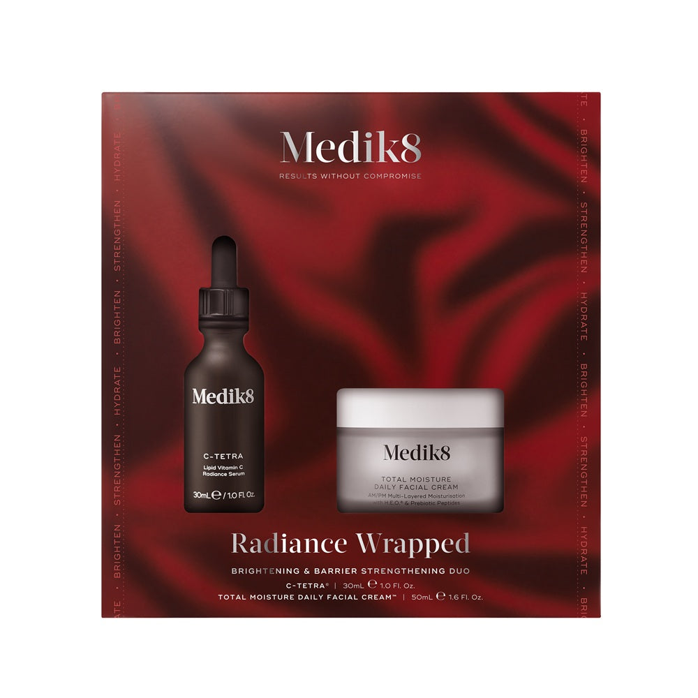 Medik8 Radiance Wrapped skincare set with serum and cream on a red fabric background