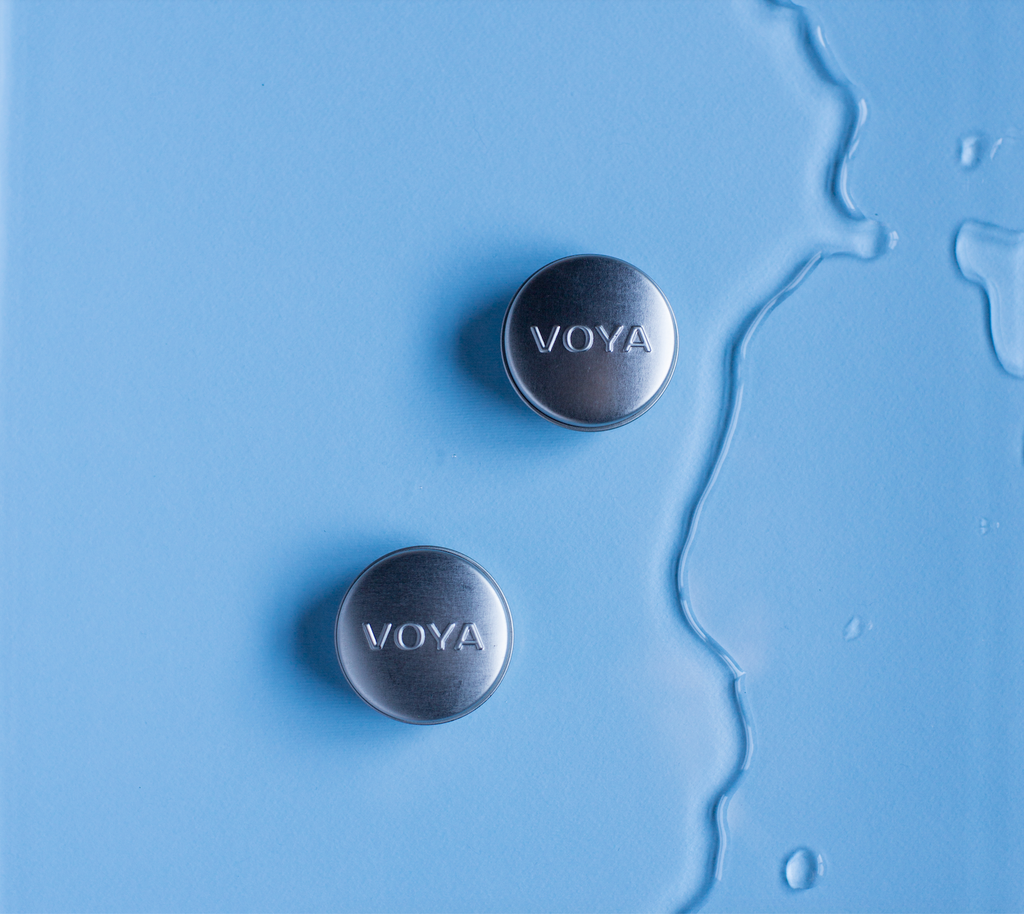 2 voya balmelicious tins on a blue background