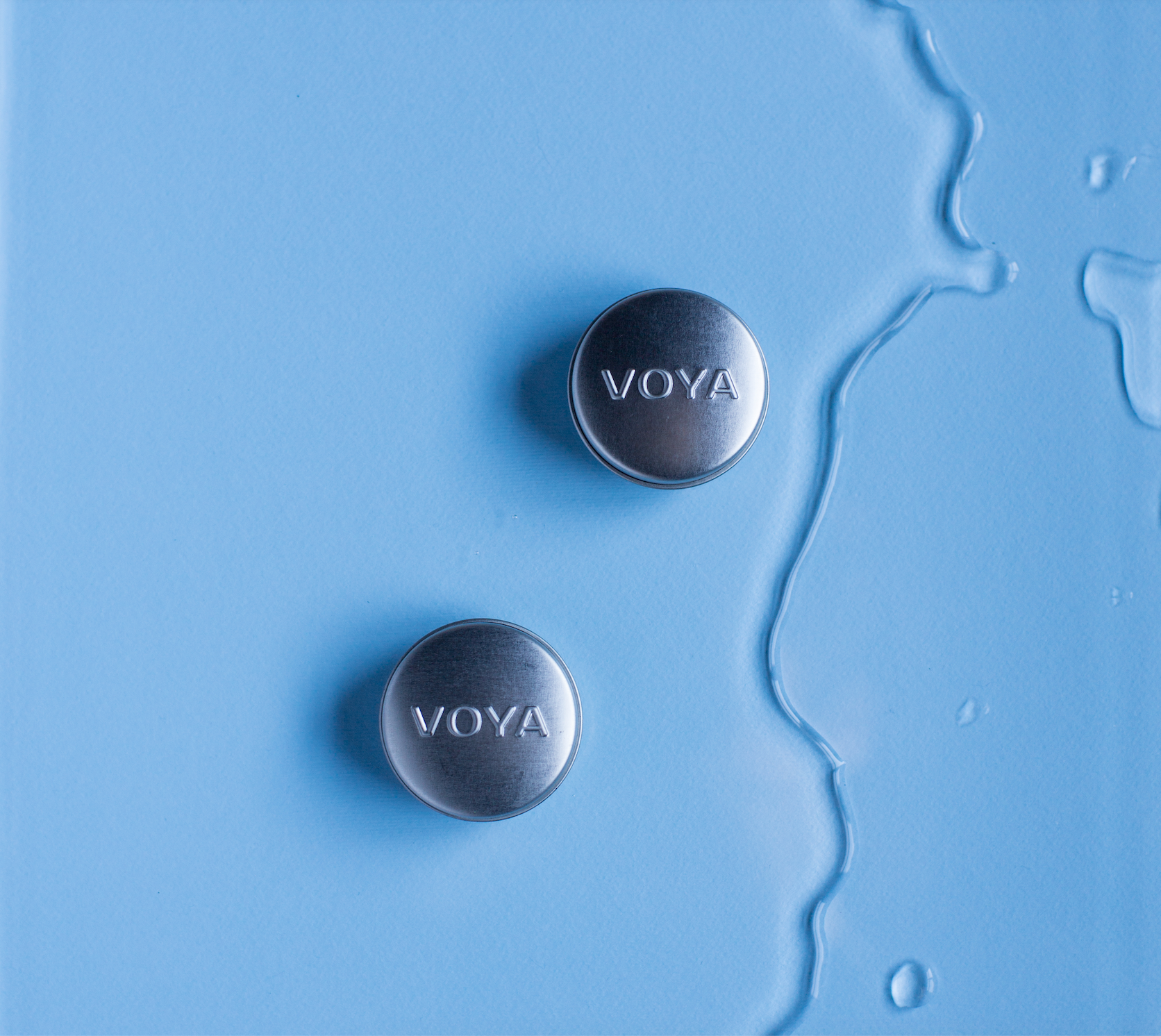 2 voya balmelicious tins on a blue background