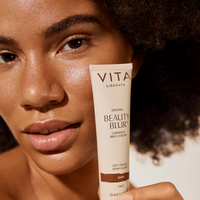 Person holding a tube of Vita Liberata Beauty Blur close to their face after applying to skin