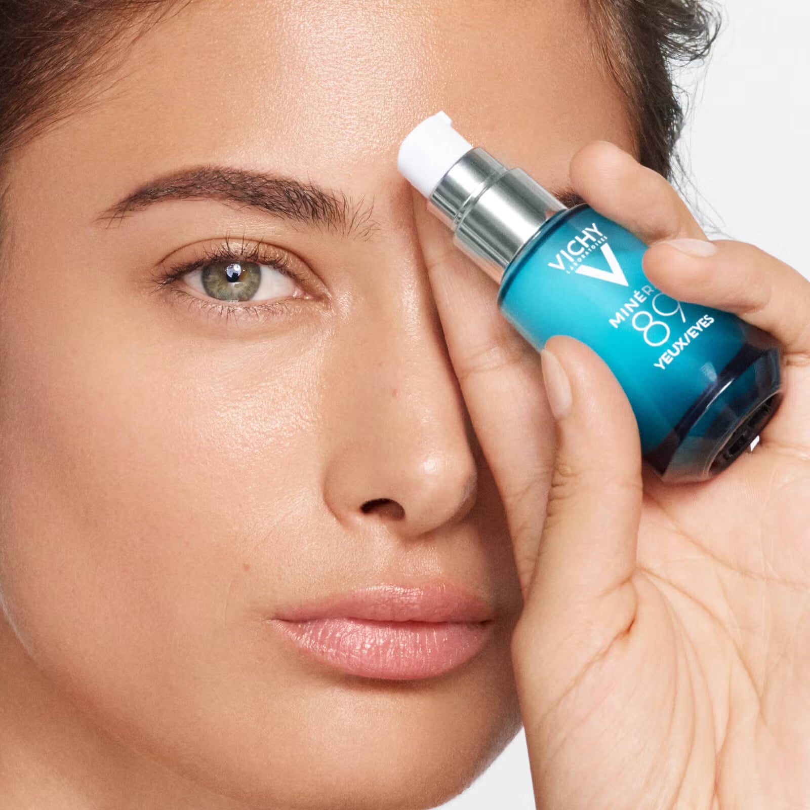 Woman holding a Vichy Vichy Minéral 89 Eyes 15 ml skincare bottle near her face