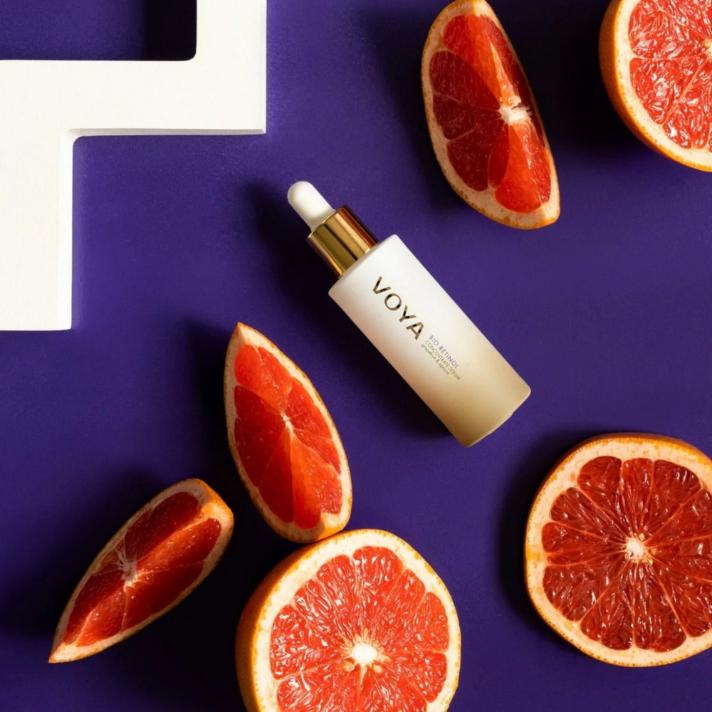 VOYA Bio Retinol Concentrate Serum 30 ml skincare dropper bottle surrounded by sliced grapefruits on a purple background