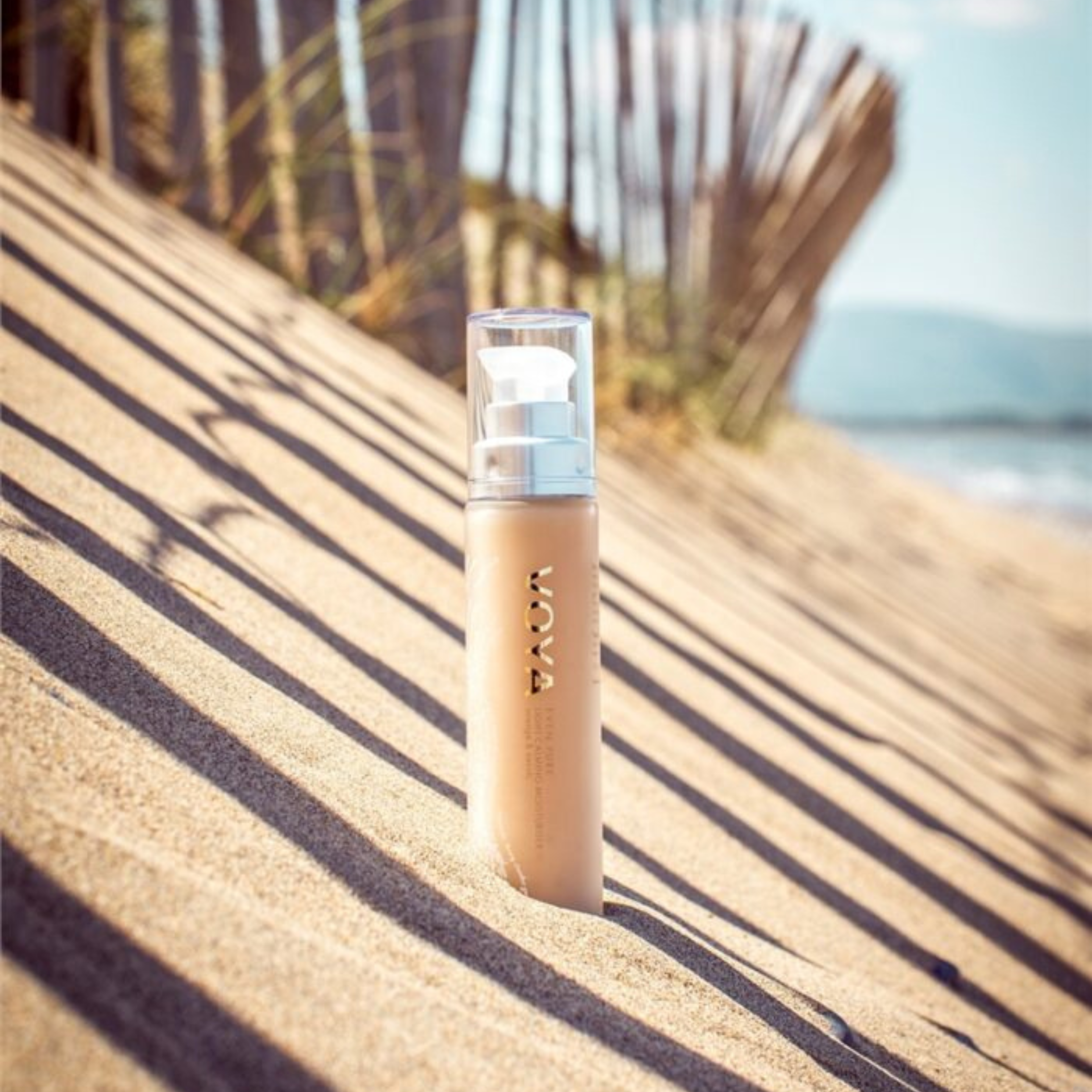 Voya Even Pure Light Calming Moisturiser in glass bottle on a sandy hill by the beach