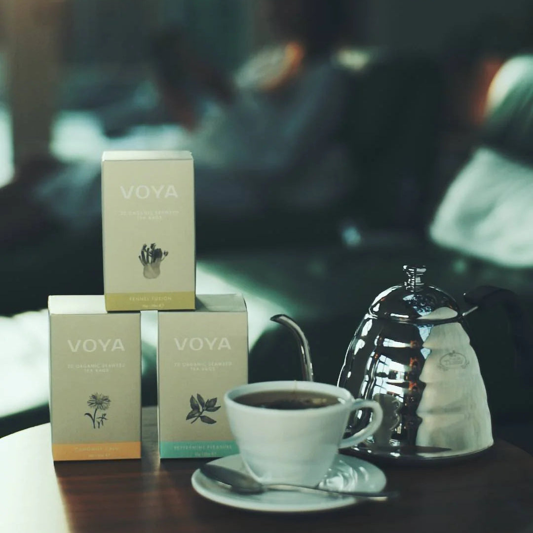Voya tea boxes with a cup of tea on a table