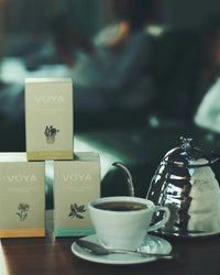 Voya tea boxes with a cup of tea on a table