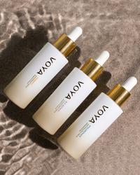 Three Voya skincare droppers on a textured brown surface