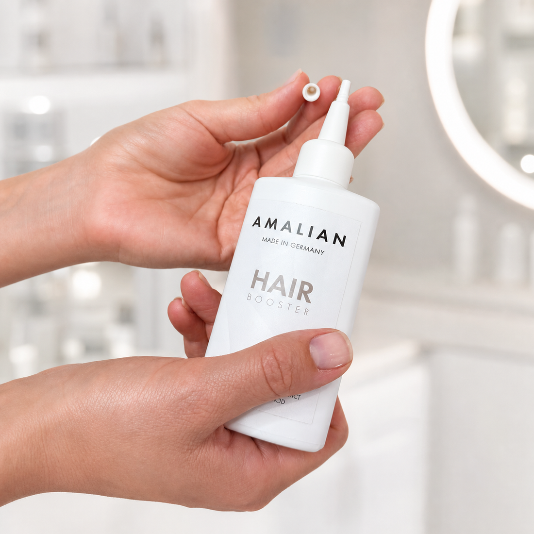 Amalian Hair Growth Booster 100ml held in hands with the precision applicator nozzle cap removed