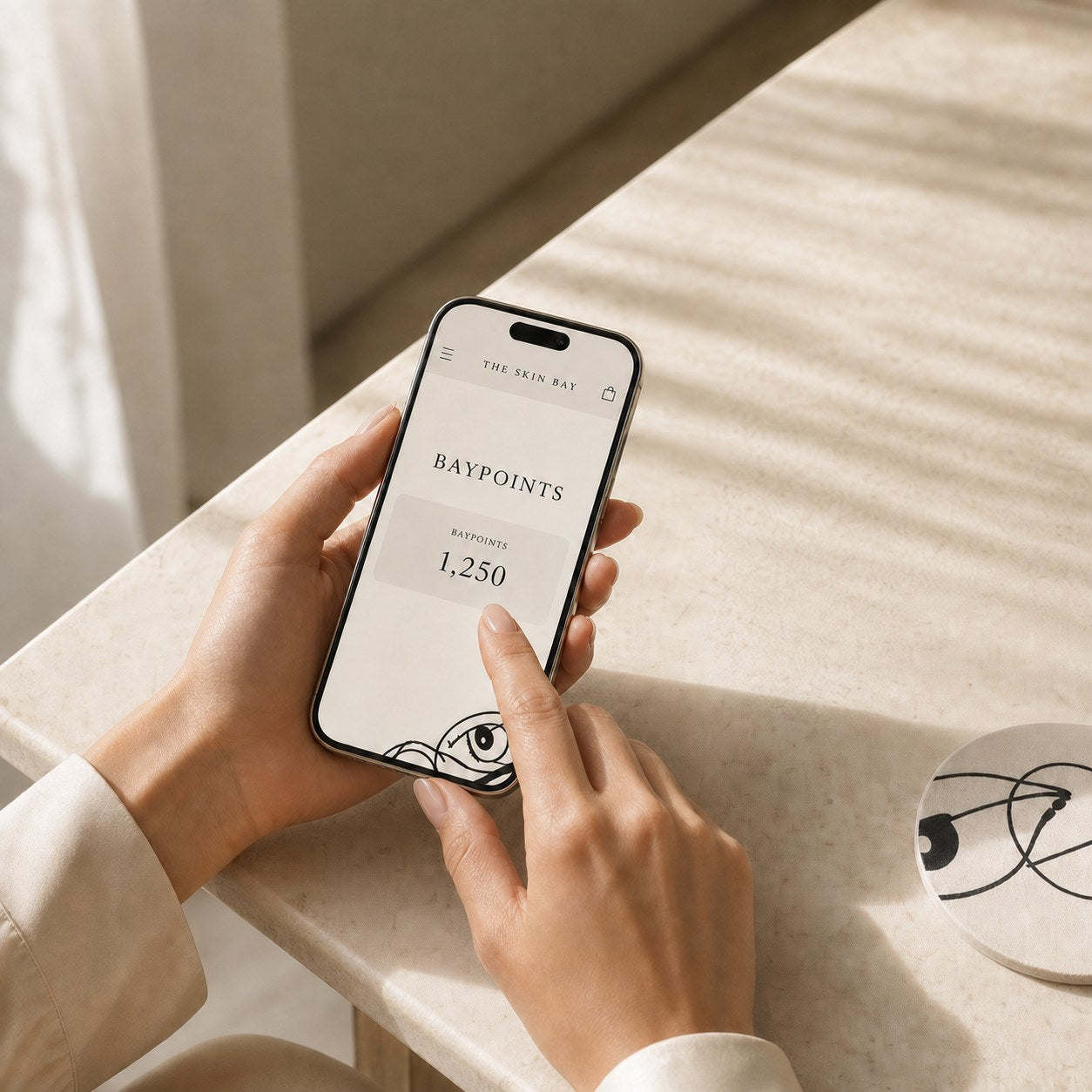A hand holding a phone showing The Skin Bay BayPoints rewards balance of 1,250 points
